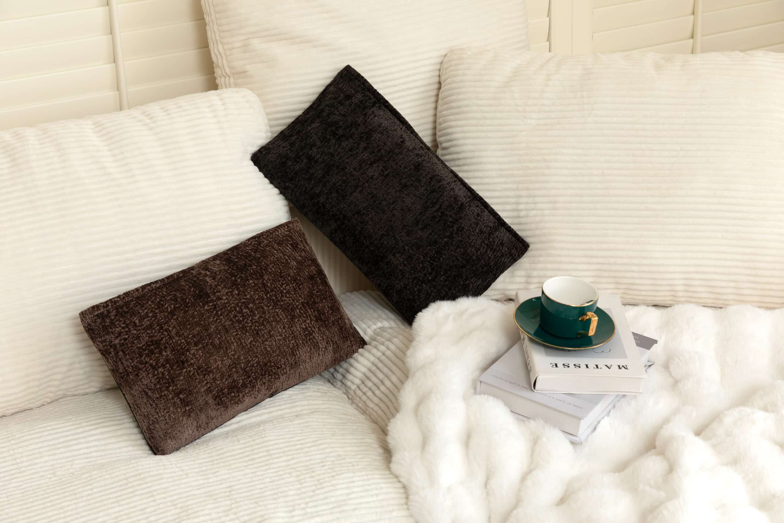 Två massagekuddar med värme placerade i vit soffa för avslappning och komfort